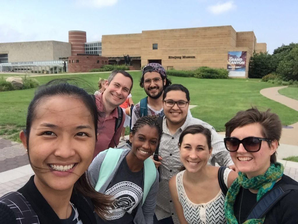 Picture of a group of young individuals standing in front of a large museum.